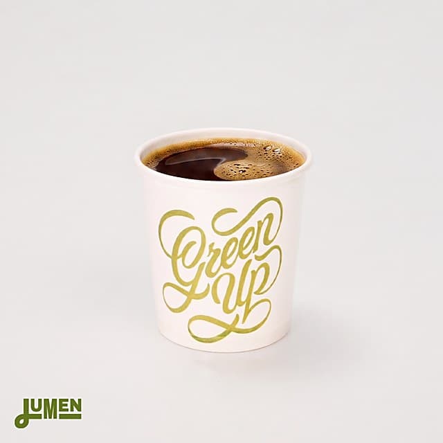 Copo de papel personalizado Lumenpack de 100 ml com arte "Green Up" servido com café.